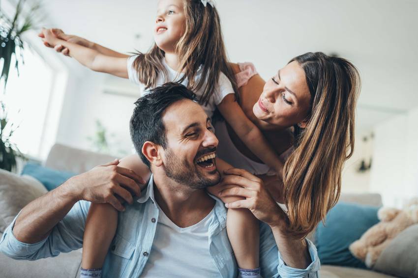mother and father with young daughter on his shoulders